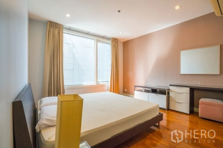 Condominium for rent or sale in Khlong Toei, Bangkok - Primary bedroom with large window, built-in desk and warm wood flooring.