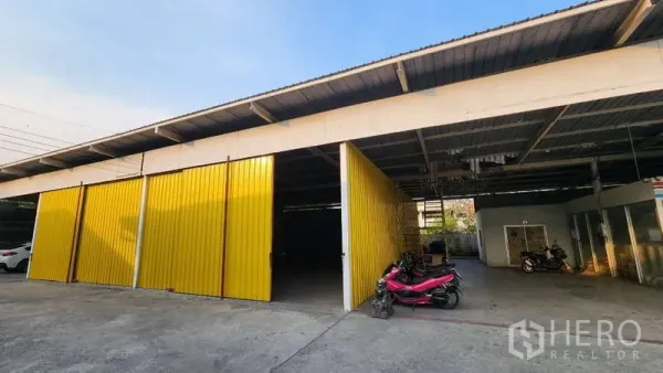 Warehouse for rent in Bang Khen, Bangkok - Covered loading bay with open yellow doors and parking area in front of the warehouse.