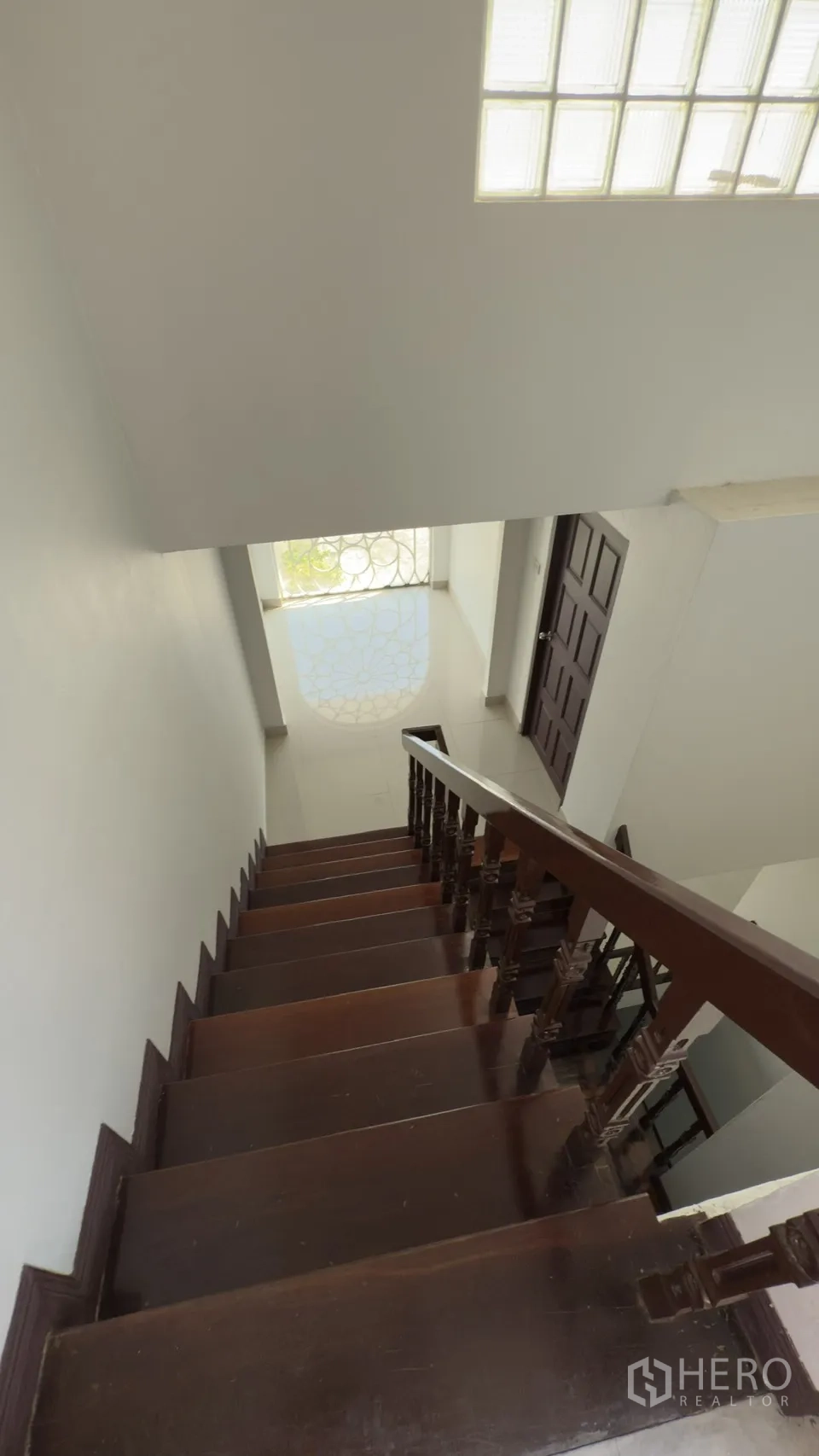Townhouse for rent in Watthana, Bangkok - Wooden staircase descending to a foyer with a patterned arched window.