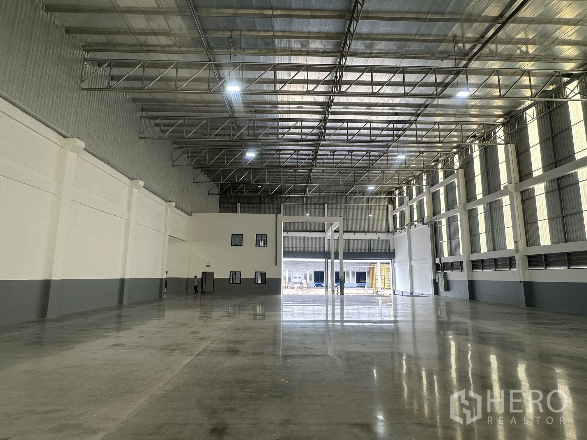 Factory for rent in Bang Phli, Samut Prakan - High-ceiling warehouse with steel trusses, tall windows, and roller shutters.