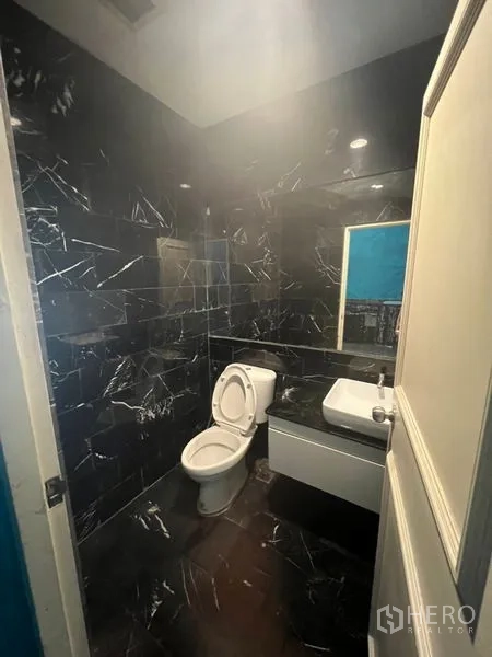 Retail Space for rent in Watthana, Bangkok - Restroom finished in black marble-look tiles with toilet and wall-mounted sink.