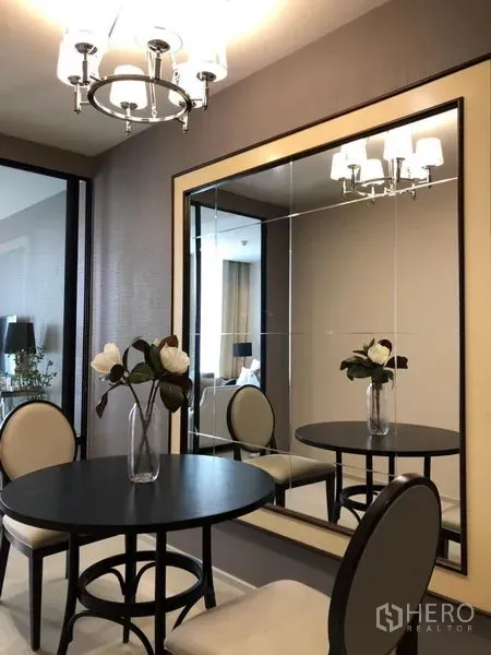 Condominium for rent in Pathum Wan, Bangkok - Cozy dining nook with round table, chandelier and an oversized mirror.