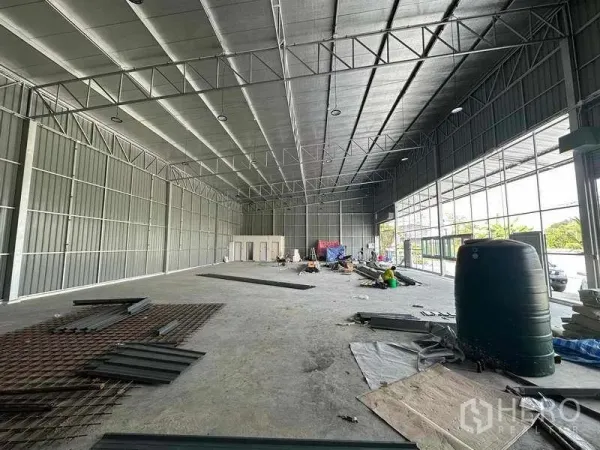 Warehouse for rent in Pak Kret, Nonthaburi - Spacious warehouse interior with high insulated ceiling, steel trusses, concrete floor and office/restroom block.