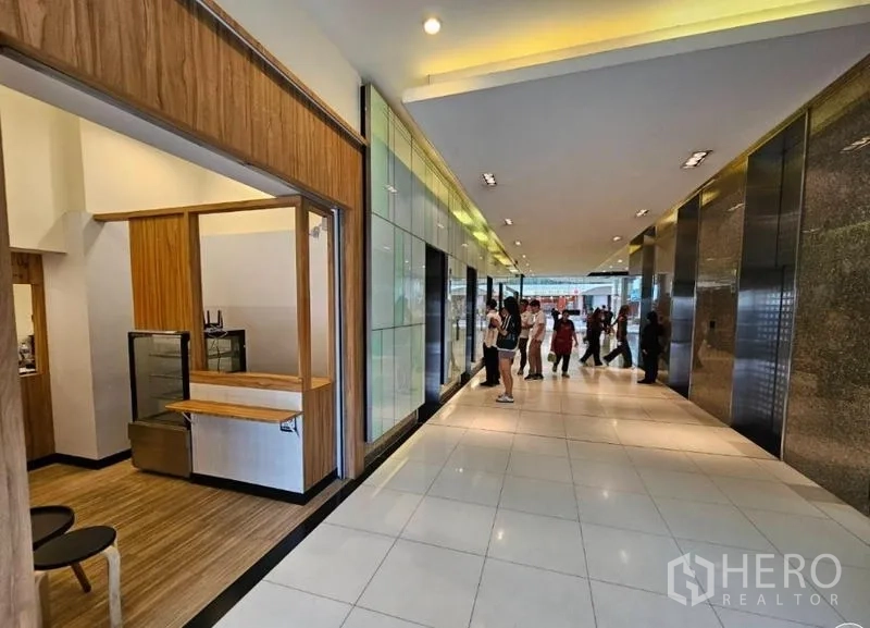 Retail Space for rent in Watthana, Bangkok - Lobby corridor with tiled floors and multiple elevators next to a shopfront and service counter.