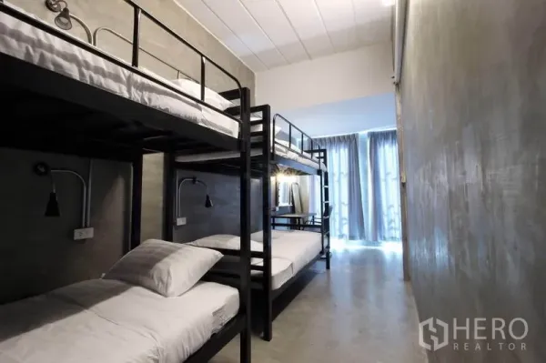 Office Space for rent or sale in Bang Rak, Bangkok - Bright bunk room with concrete floors and floor-to-ceiling curtains.