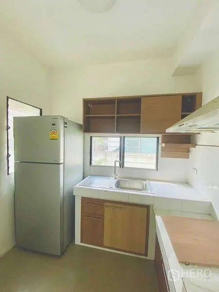Detached House for rent - Practical kitchen with cabinets, sink, extractor and a refrigerator by the window.