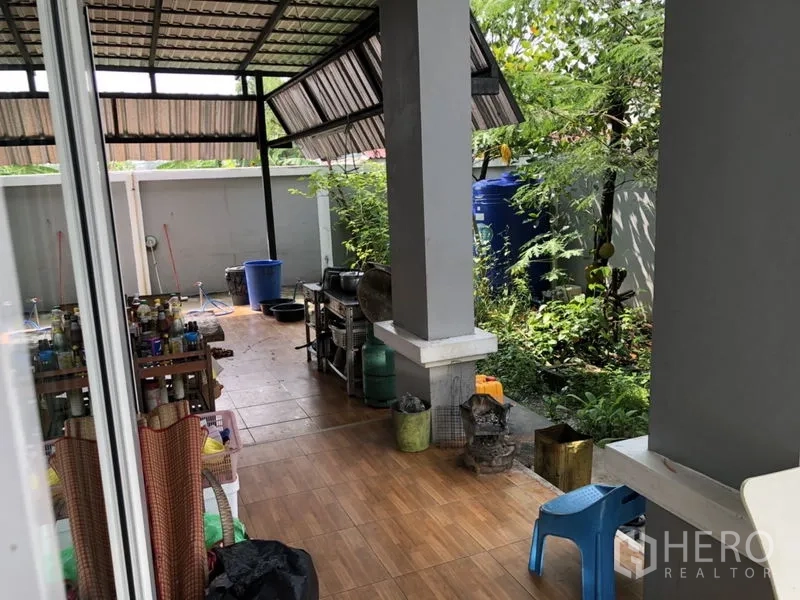 Detached House for sale in Lam Luk Ka, Pathum Thani - Covered outdoor Thai kitchen and utility area beside a small garden.