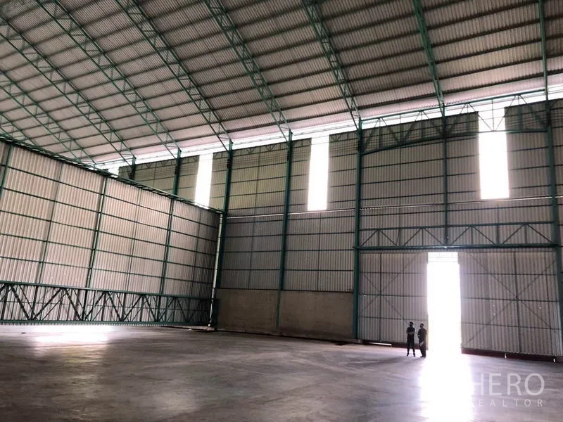 Warehouse for rent in Sai Noi, Nonthaburi - Sunlit entrance wall with towering doors and vertical light panels inside the warehouse.