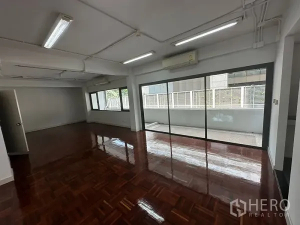 Office Space for rent - Spacious open‑plan office with polished parquet flooring and sliding glass doors to a balcony.