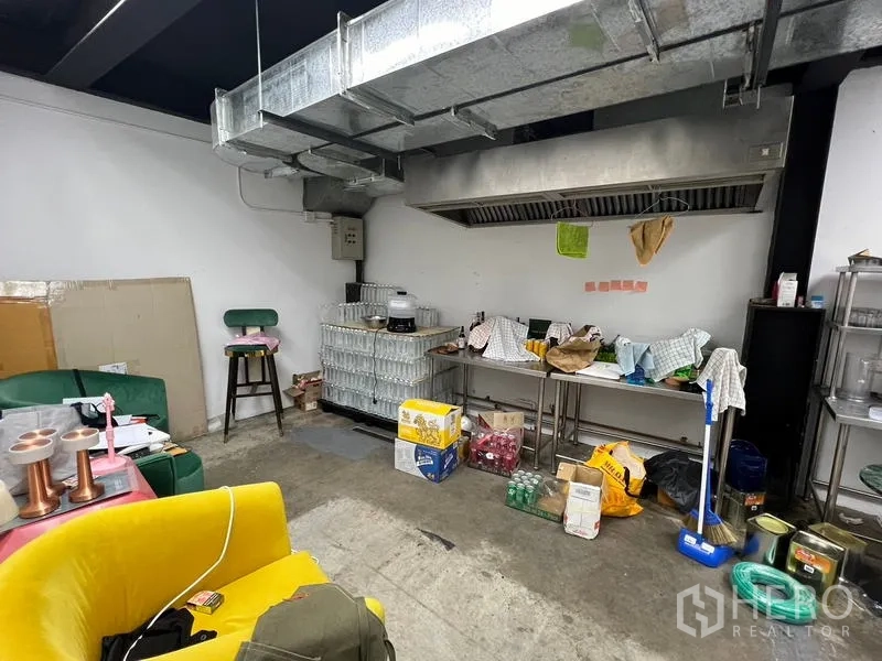 Retail Space for rent in Watthana, Bangkok - Commercial kitchen area with large extraction hood, supplies, and concrete floor.