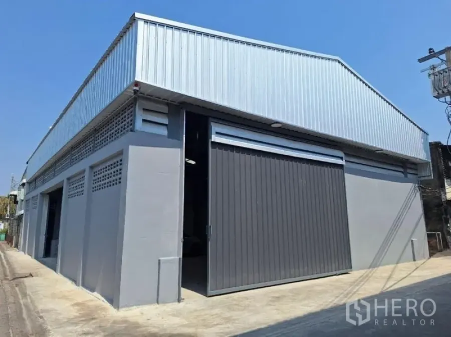Warehouse for rent in Rat Burana, Bangkok - Street-side facade of the warehouse with grey walls and an oversized sliding gate.