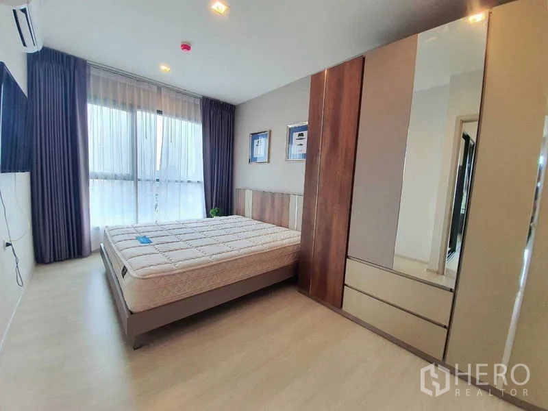 Condominium for sale in Khlong Toei, Bangkok - Master bedroom featuring wardrobe with mirrored doors and wide windows.