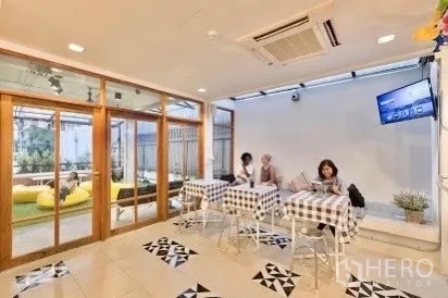 Shophouse for rent in Pathum Wan, Bangkok - Bright cafe-style dining area with checkered tables and sliding glass doors to the terrace.