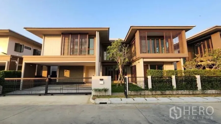 Detached House for rent or sale in Bang Kapi, Bangkok - Front elevation of the two‑storey home with carport and neatly trimmed hedge.