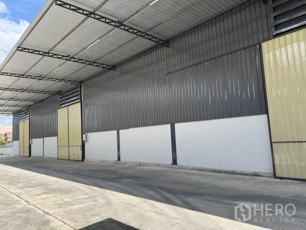 Warehouse for rent in Phra Nakhon Si Ayutthaya, Phra Nakhon Si Ayutthaya - Covered loading bay with multiple sliding doors and wide concrete apron along the warehouse exterior.