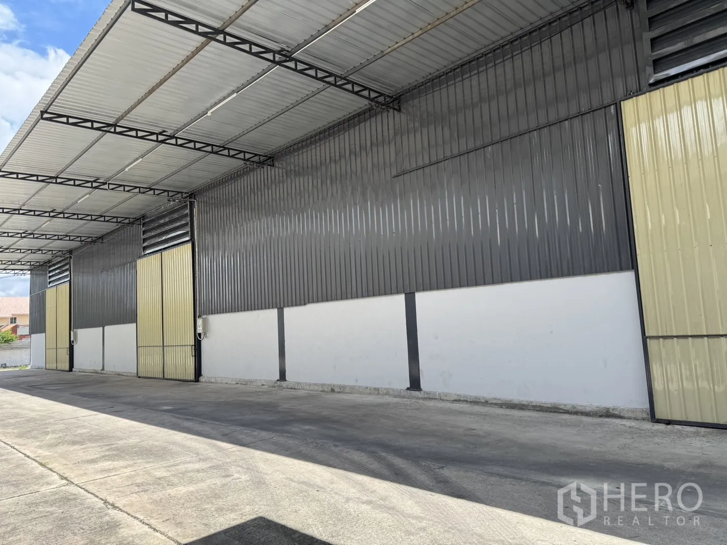 Warehouse for rent in Phra Nakhon Si Ayutthaya, Phra Nakhon Si Ayutthaya - Covered loading bay with multiple sliding doors and wide concrete apron along the warehouse exterior.