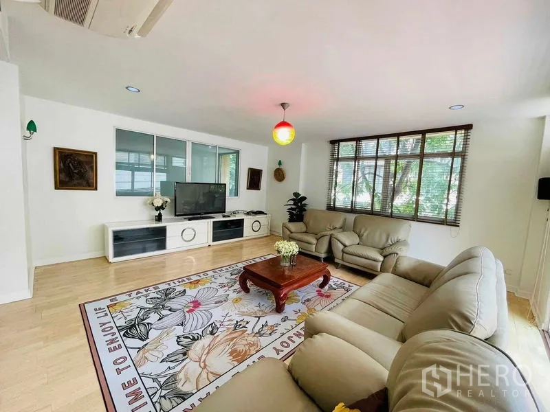 Detached House for rent in Watthana, Bangkok - Airy living room view with full-height windows, TV unit, and neutral decor.