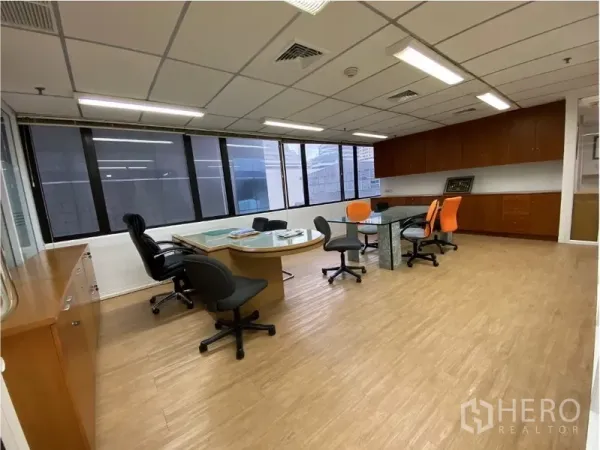 Office Space for rent in Khlong Toei, Bangkok - Open-plan office with large windows, wood flooring, meeting tables and built-in storage cabinets.