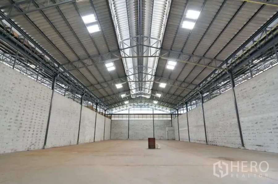 Warehouse for rent in Phra Pradaeng, Samut Prakan - Spacious warehouse interior with high steel truss roof, skylights and concrete floor.
