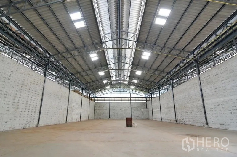 Warehouse for rent in Phra Pradaeng, Samut Prakan - Spacious warehouse interior with high steel truss roof, skylights and concrete floor.