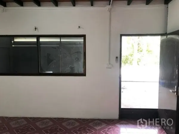 Warehouse for rent in Lam Luk Ka, Pathum Thani - Office area with sliding window and glass door opening to the outside from within the warehouse.
