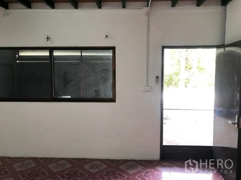 Warehouse for rent in Lam Luk Ka, Pathum Thani - Office area with sliding window and glass door opening to the outside from within the warehouse.