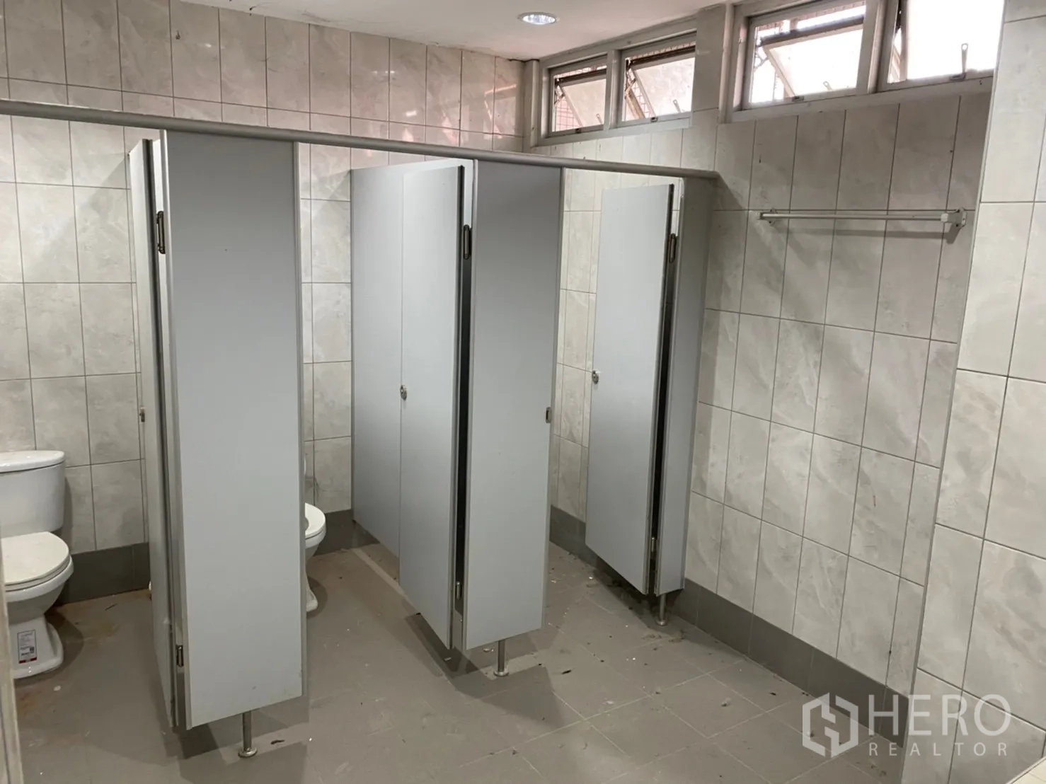 Warehouse for rent in Lat Krabang, Bangkok - Row of separate toilet stalls with tiled walls and ventilation windows.