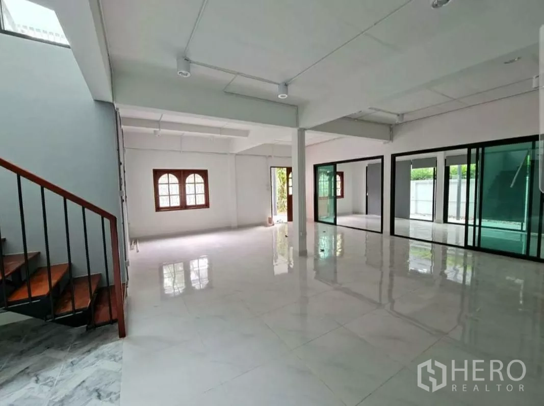 Home Office for rent in Lat Phrao, Bangkok - Open‑plan ground floor with glossy white tiles, glass partitions and abundant light.