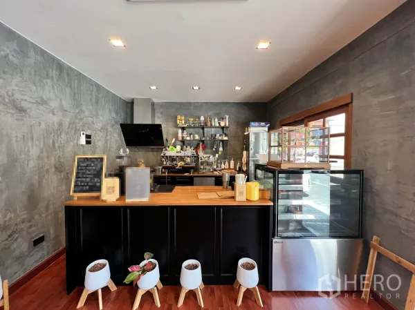 Retail Space for rent in Watthana, Bangkok - Service counter with wood top, black cabinetry, espresso setup, display fridge, and wall shelving.