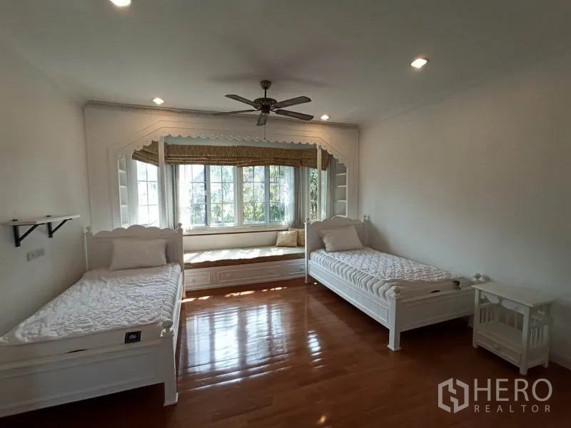 Detached House for rent in Mueang Samut Prakan, Samut Prakan - Twin bedroom with ceiling fan, bay window daybed and polished wooden floors.