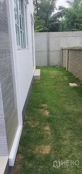 Detached House for rent in Nonthaburi - Neat side yard with green lawn and privacy wall beside the house in Pak Kret, Nonthaburi.