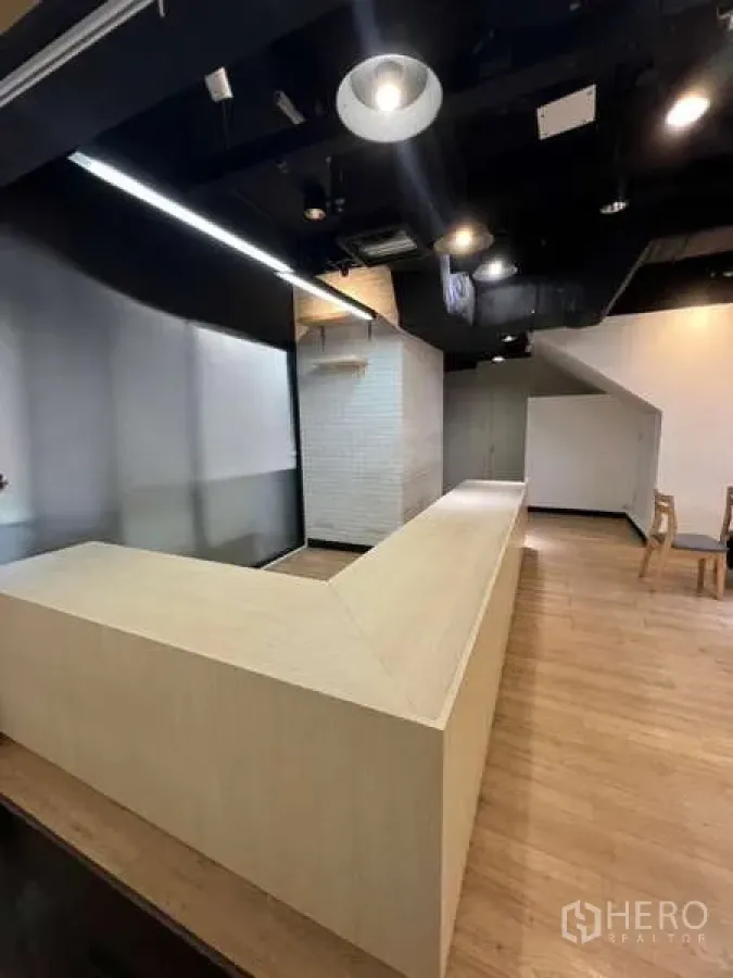 零售空间 出租在Watthana, Bangkok - 现代店铺内，长L形柜台与黑色高顶射灯。