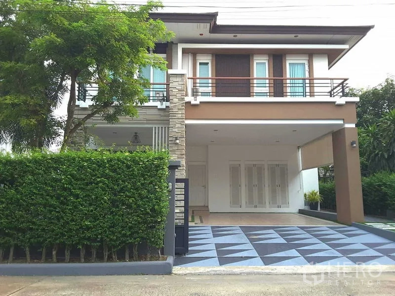 Detached House for rent in Lam Luk Ka, Pathum Thani - Contemporary two-storey detached house with hedge fence, covered carport and patterned driveway.