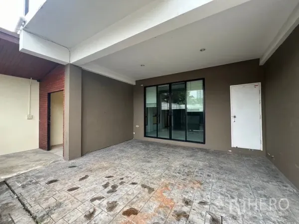 Townhouse for rent or sale in Khlong Toei, Bangkok - Covered carport of the townhouse with stamped concrete, sliding glass doors and a side storage door.