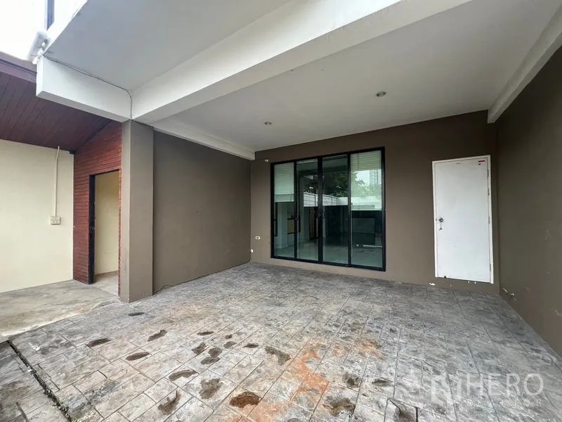 Townhouse for rent or sale in Khlong Toei, Bangkok - Covered carport of the townhouse with stamped concrete, sliding glass doors and a side storage door.