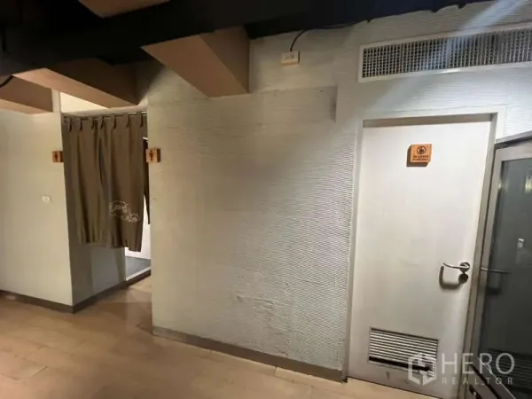Shophouse for rent or sale in Khlong Toei, Bangkok - Interior corridor with light wood floor, textured walls and service doors in the shophouse.