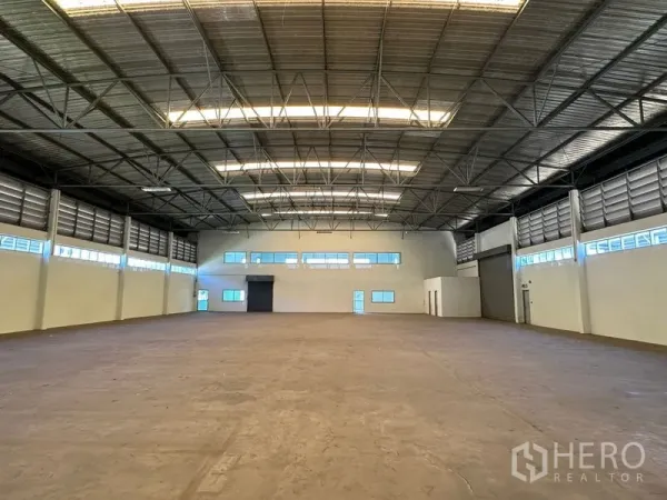 Factory for rent in Chon Buri - Spacious warehouse floor with high steel-truss roof, skylights, and ventilation louvers along the sides.