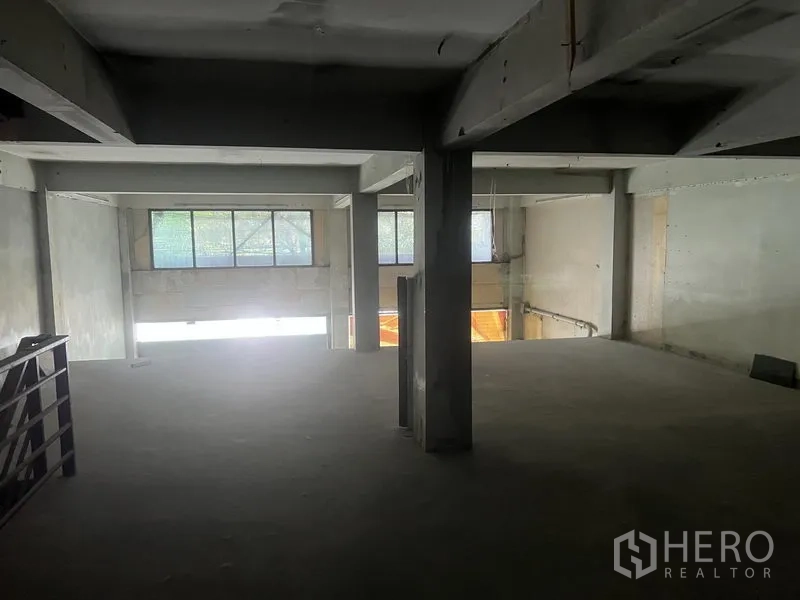 Shophouse for rent in Watthana, Bangkok - Mezzanine level overlooking the lower floor with beams, pillars, and windows.