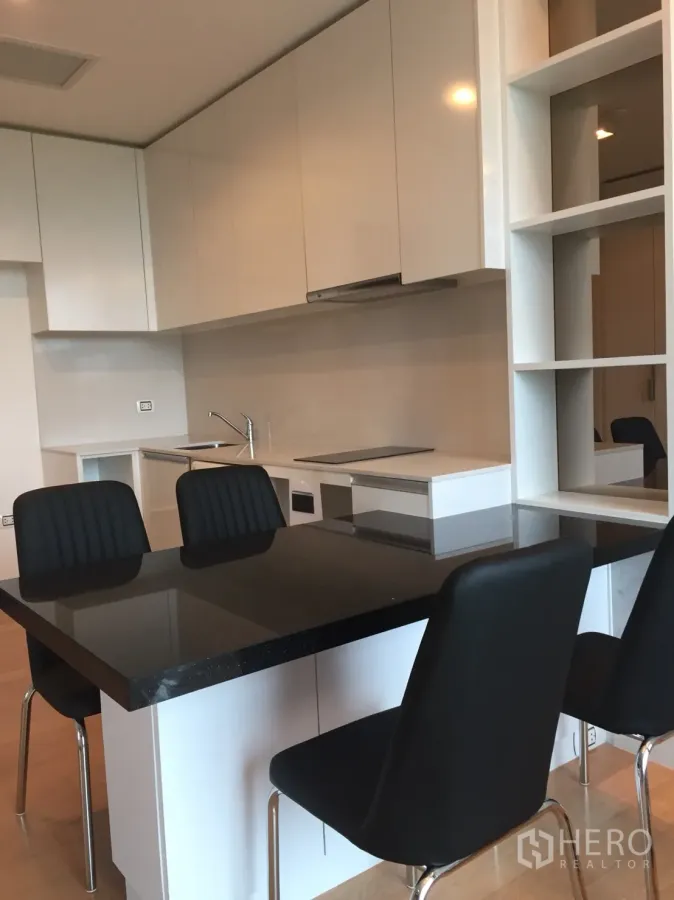 Condominium for rent in Chatuchak, Bangkok - Modern white kitchenette with black stone island and three chairs