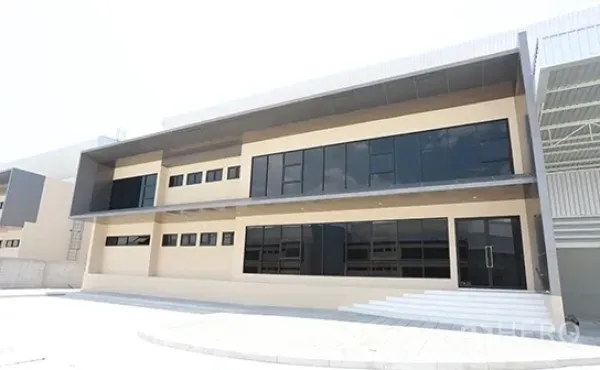 货栈 出租在Bang Pakong, Chachoengsao - 现代两层仓库与办公楼外立面，深色玻璃与雨篷
