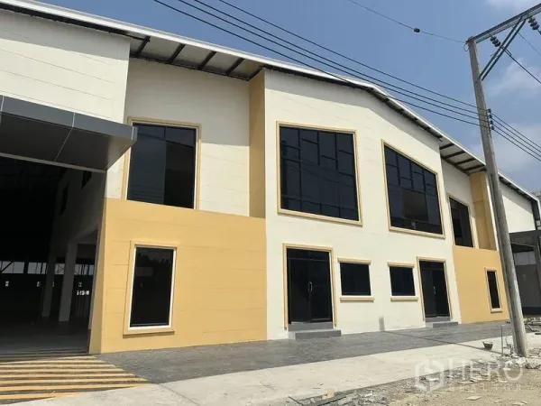 Warehouse for rent in Bang Pakong, Chachoengsao - Front facade of new warehouse with tinted windows, paved frontage and a covered loading bay.