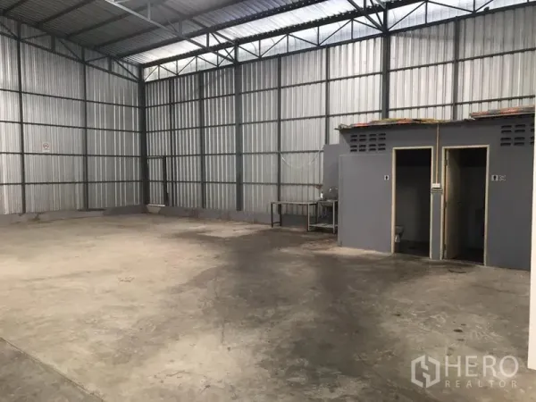 Warehouse for rent in Wang Thonglang, Bangkok - Warehouse corner featuring built-in restrooms and a utility sink beneath high corrugated walls.