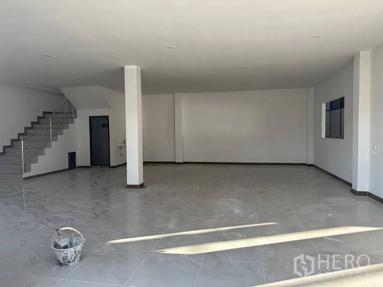 Factory for rent in Nong Khaem, Bangkok - Open‑plan ground‑floor office with staircase, polished tiles and window facing the warehouse.