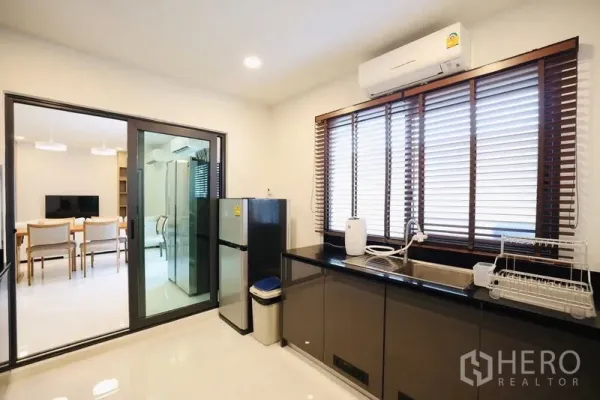 Detached House for rent in Bang Phli, Samut Prakan - Enclosed kitchen with black countertops, window blinds, and a stainless refrigerator.