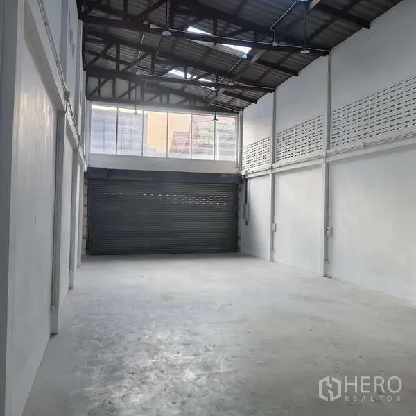 Shophouse for rent in Khlong Toei, Bangkok - Ground floor area with high windows and motorized roller shutter door.