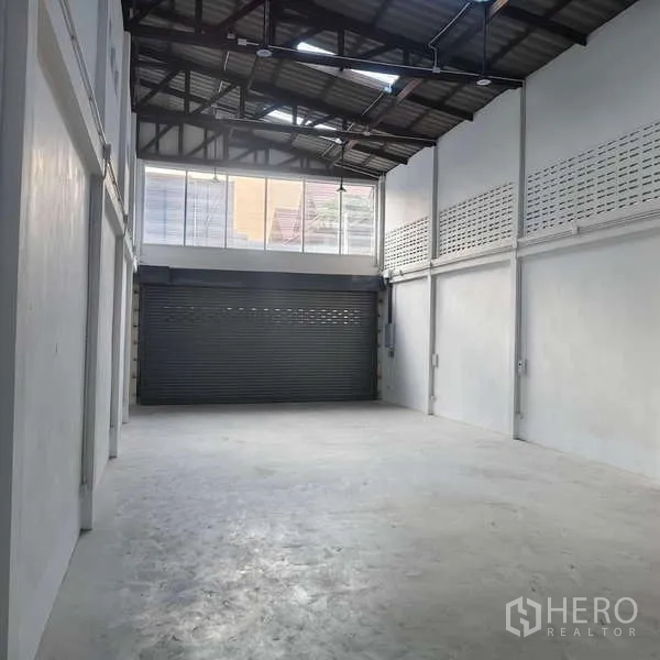 Shophouse for rent in Khlong Toei, Bangkok - Ground floor area with high windows and motorized roller shutter door.