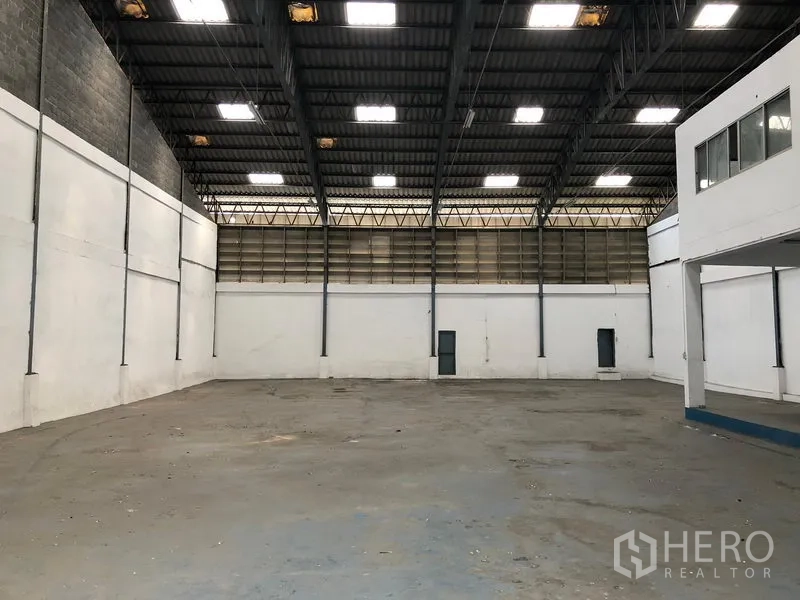 Warehouse for rent in Bang Phli, Samut Prakan - Open warehouse floor with high clearance, bright roof panels, and side access doors.