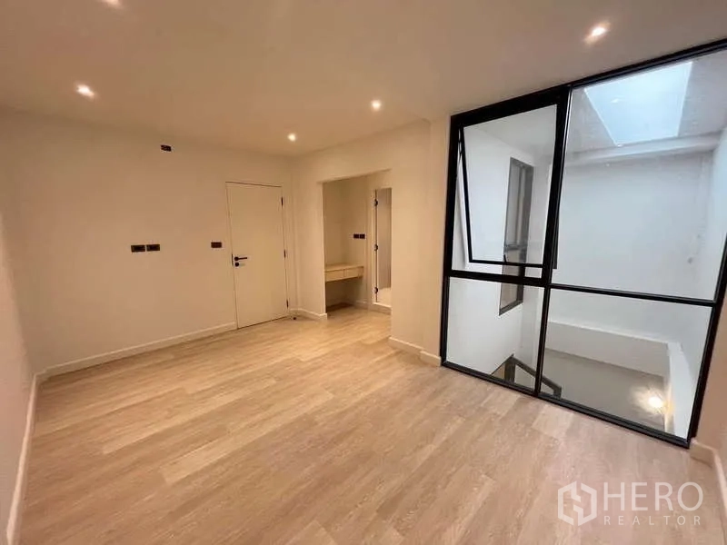 Townhouse for sale in Khlong Toei, Bangkok - Room with large internal glass wall, vanity niche and ceiling spotlights.