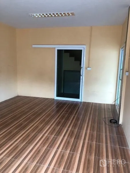 Warehouse for rent in Pak Kret, Nonthaburi - Ground-floor office room with wood-look tile flooring and a sliding glass door.