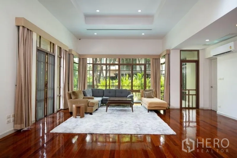 Detached House for rent in Watthana, Bangkok - Living room facing the garden with expansive windows and recessed ceiling lights.
